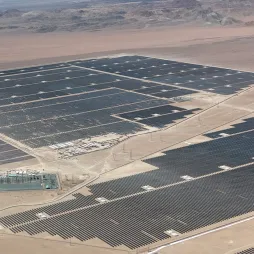 Aerial view of the AES Andes solar facility in Chile featuring extensive rows of photovoltaic panels across a desert landscape with supporting electrical infrastructure.